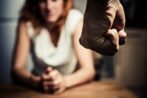 Image of a women blurred in the background and a single clinched fist to illustrate domestic abuse.